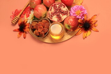 Honey, apples, pomegranates, flowers, dried fruits on a warm orange background, composition for the...