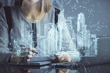 Double exposure of woman hands typing on computer and buildings drawing. Smart-city concept.