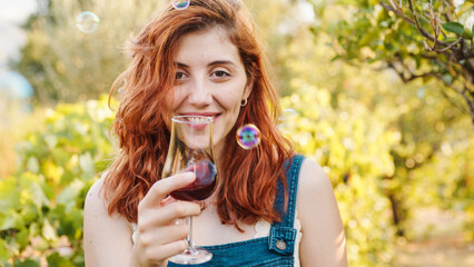 Happy woman with glass of wine in the vineyard