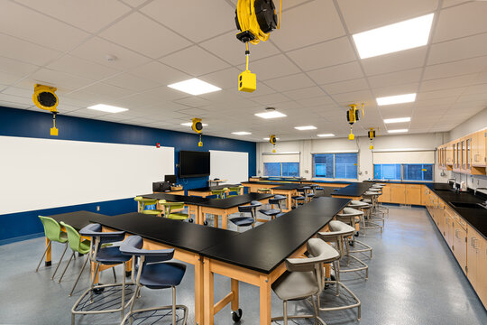 Example of a new empty nondescript US High School science classroom with desks, chairs, windows, and white board.  Classroom could be in almost any US High School.  Nobody included in image.