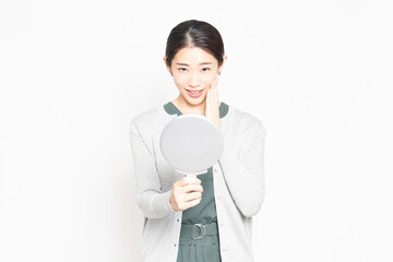 鏡を見て肌のチェックをする女性