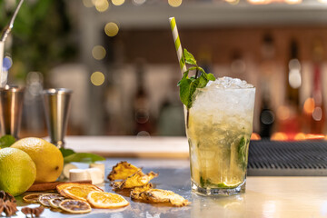 Mojito cocktail on bar counter with lemons, limes and species with copy space for text.
