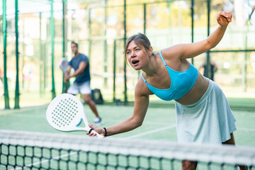 Active womans with enthusiasm playing padel on the tennis court