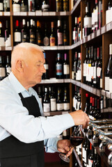 positive senior man professional sommelier pouring wine from wine column