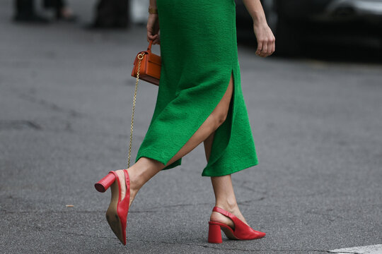 woman wearing green skirt, red shoes and red purse