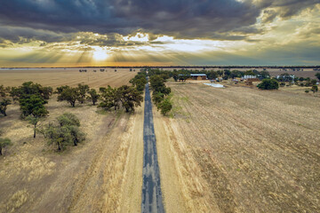 Looking down over a dirt road leading into the distance with the setting set.