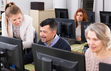 Serious businesswoman helping to man, pointing at computer monitor in office