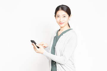 白背景の前でスマホを操作している女性