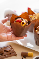 Chocolate cupcake.Appetizing muffin cupcakes in hand on the table with sweets and pastries background.Chocolate dessert. Assorted sweet table. Sweets and desserts. Baked goods and desserts