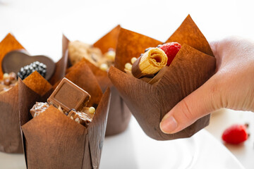 Chocolate muffin in hand on the table with sweets and pastries .Chocolate dessert. Assorted sweet table. Baked goods and desserts