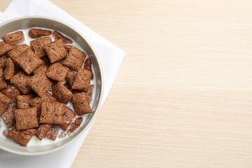 Bowl with tasty corn pads and milk on wooden table, flat lay. Space for text