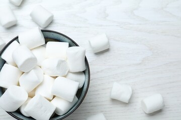 Delicious puffy marshmallows on white wooden table