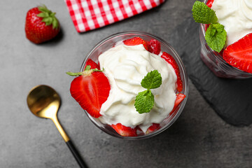 Delicious strawberries with whipped cream served on grey table, flat lay
