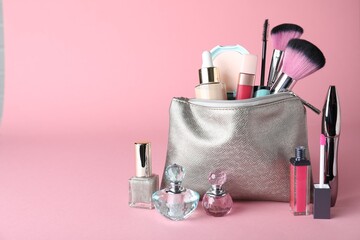 Cosmetic bag and makeup products with accessories on pink background. Space for text