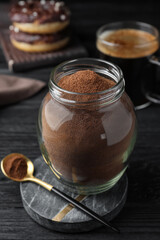 Obraz na płótnie Canvas Jar of instant coffee and spoon on black wooden table