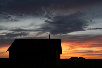 An old rustic farm building silhouette on the Alberta prairies at sunrise in Rocky View County Canada