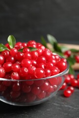 Fresh cranberry in bowl on dark grey table, closeup