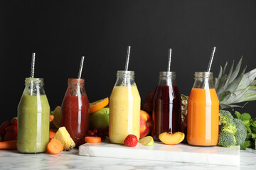 Fototapeta na wymiar Bottles of delicious juices and fresh fruits on white marble table
