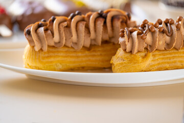  cakes with chocolate cream and chocolate decor on a beige background.Choux pastry. Summer desserts.Sweets and desserts. Baked goods and desserts.Eclairs cakes.