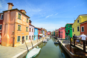 Naklejka na ściany i meble Tourists among the sovereign shops on the main street of burano Island, Colorful houses on the canal. Venice, Italy.