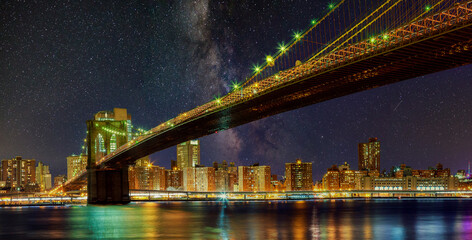 Naklejka na ściany i meble Brooklyn Bridge by night with skyscrapers famous New York panoramic view of Manhattan skyline