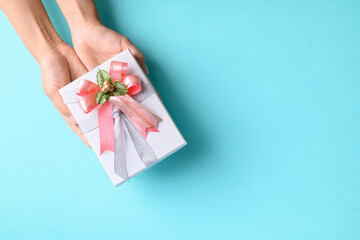 Silver gift box with pink ribbon in hand on light blue color background, Present for giving in special day and holiday