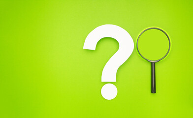 A magnifying glass and a white question mark symbol are on a light green background