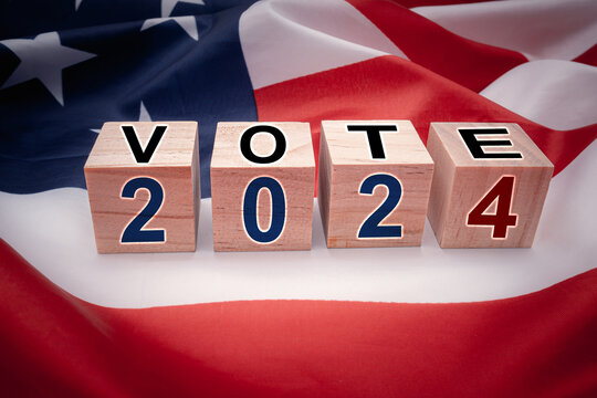 United States presidential election in 2024. Wooden cubes with text VOTE and 2024 over the American flag background