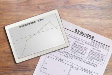 日本全国住宅地価変動率グラフと不動産専任媒介契約書