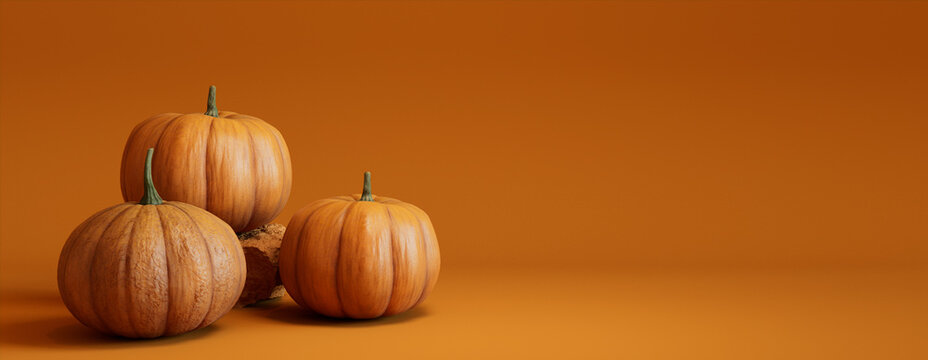 Three Pumpkins on a Orange colored background. Autumn themed Banner with copy-space.