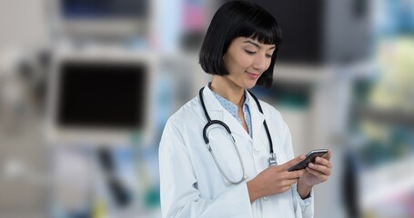 Smiling asian young female doctor using smart phone while standing in hospital - Powered by Adobe
