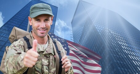 Fototapeta premium Portrait of caucasian mid adult male soldier showing thumbs up against buildings in city