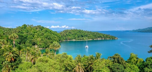 Beautiful tropical landscape scene in Puerto Galera on Mindoro Island, Philippines, showing a yacht anchored in secluded Encenada Bay.