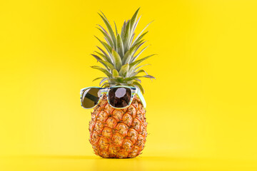 Fototapeta Creative pineapples with sunglasses isolated on yellow background, summer vacation beach idea design pattern, copy space, close up, blank for text obraz