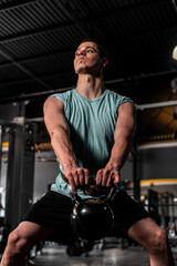 Fototapeta na wymiar Caucasian man training in the gym performing training. Man lifting a kettlebell with a lot of effort. High quality photo