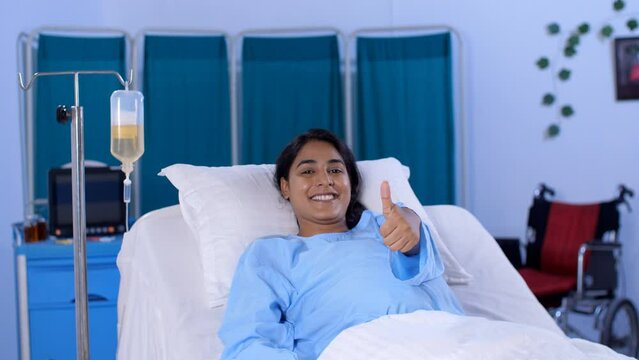 A young female patient is doing a thumbs-up gesture in the hospital ward - well being  cheerful. A sick girl in her twenties is admitted to the hospital - medical assistance  health and medical  tr...