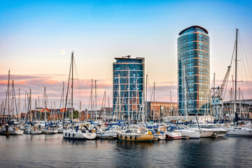 Chatham maritime marina at sunset. Reflection on water, yachts, two modern skyscrapers on background, moon and copy space in clear sky.