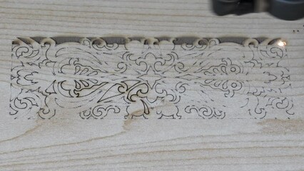 Traditional motifs engraved on wood with CNC laser machine. Image of computer-controlled cnc laser machine for engraving motifs on wood.