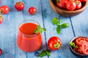 Tomato juice with basil in glasses and vegetables on the table. Organic homemade drinks