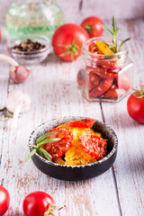 Dried tomatoes with spices and garlic in a bowl and fresh vegetables on the table. Vertical view