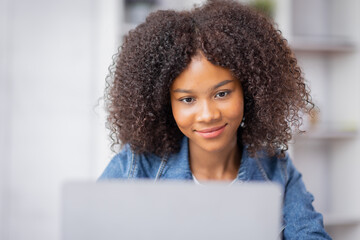 Creative young african american woman working and talking on laptop in her studio