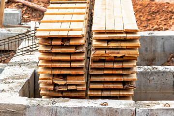 Wooden formwork boards stacked at the construction site. Storage of building materials at the construction site. Formwork for strip foundation.
