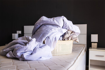 bed linen in a large pile lies in a basin, prepared for washing