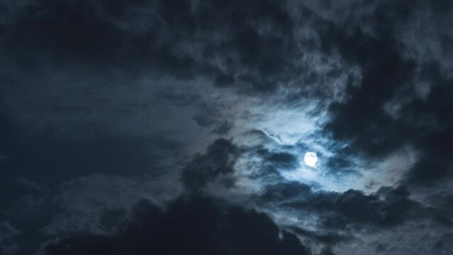 Nighttime Timelapse. There is a full moon and black clouds in the sky. Beautiful moonlight and twinkling stars