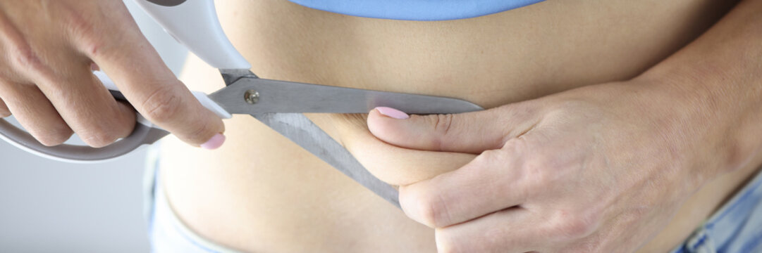 Woman cuts off piece of fat with scissors closeup