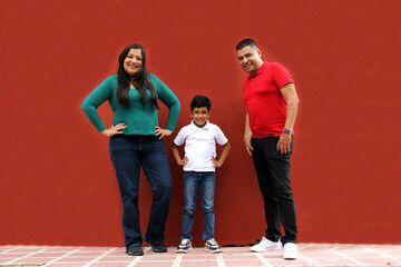 Latin mom, dad and son dressed in the colors of the Mexican flag: green, white and red proud of their tradition and culture of Mexico celebrate the national holidays
