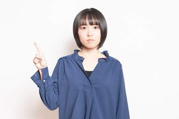 白背景の前で、ポイントを示す若い女性