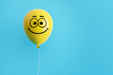 Yellow flying air helium balloon with smiling emoticon face against blue background. Happiness, positivity, optimism © Cagkan