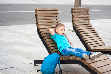 A boy in a blue T-shirt is resting on a chaise longue that stands on the embankment. Journey.  The...