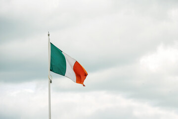 National flag of Ireland on cloudy sky background with copy space for message. Irish tri color.